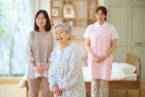 介護職員と高齢者が手を繋いで交流している施設の室内風景